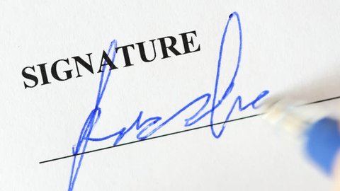 Signing official document with a blue ink pen. Closeup shot of the signature.