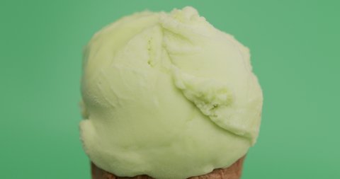 Ice cream lime scoop in waffle cone on green background.