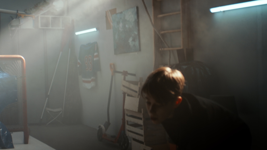 Kid boy hockey player practicing shots inside a covered garage at home. Shot with 2x anamorphic lens