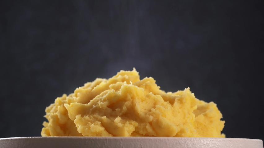 Mashed potatoes with steam on plate close up rotates