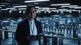 Handsome Smiling IT Specialist Using Tablet Computer in Data Center, Looking at Camera. Succesful Businessman and e-Business Entrepreneur Overlooking Server Farm Cloud Computing Facility. Medium Wide - Powered by Shutterstock - Get 15% off with code: PIKWIZARD15