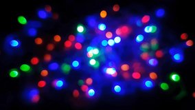 Beautiful abstract blur bokeh background of shiny colorful glowing small bubble like small circular decoration bokeh light bulbs blinking on blurry black night. Christmas and new year evening 4k video