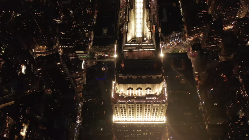 Slow Scenic turn circle around Empire State Building top at Night Illuminated, Aerial Establisher of Manhattan Skyscraper with City Lights Circa September 2019