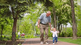 Grandfather holding baby hands helping to do first steps, family support, lovely relationship. - Powered by Shutterstock - Get 15% off with code: PIKWIZARD15
