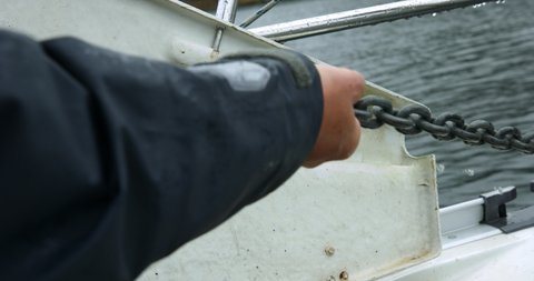 Man Manually Pulling Anchor Chain On Boat From The Ocean In Alaska. - close up