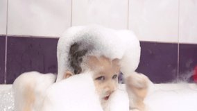 Close-up video of a happy smiling little boy with a lot of soap suds on his head and face.