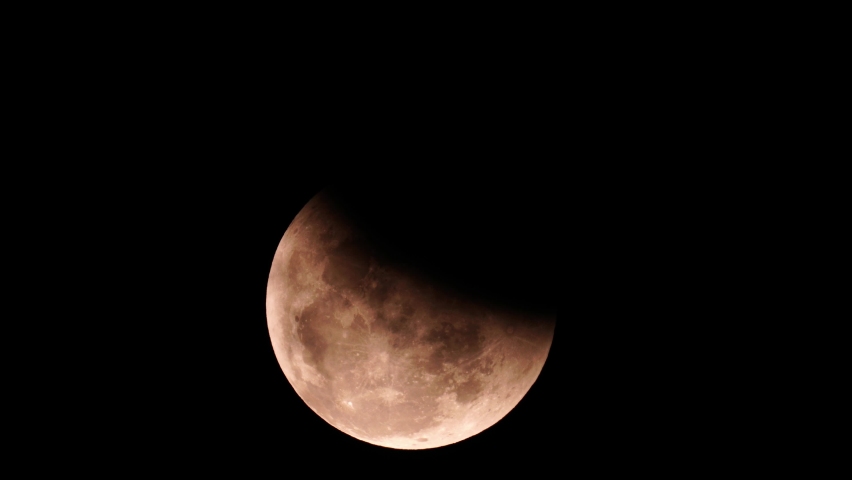 Super flower blood moon lunar eclipse rising slowly over the sky of  sarawak, malaysian borneo on 26-may-2021 with some moving clouds. captured  in 4k25p.