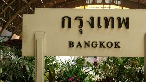 BANGKOK, THAILAND - 11 JULY, 2019: Signpost with name of city. Hua Lamphong main railroad station of state railway transport, SRT. Platform near sign board and trains on tracks