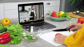 Woman in kitchen study online video conference call webcam laptop slices tomato on cutting board listen chef teacher. Man food blogger in computer screen tells teaches housewife remote cooking course