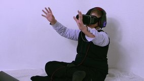 A boy in an augmented reality headset laughs and grabs his glasses with his hand. Close-up of a Caucasian child in a vr headset touching invisible things in a bright room on a white background.
