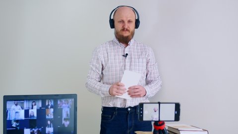 Online English training. A bald man with a beard gives a grammar lesson using flashcards to learn letters. Man in headphones and microphone