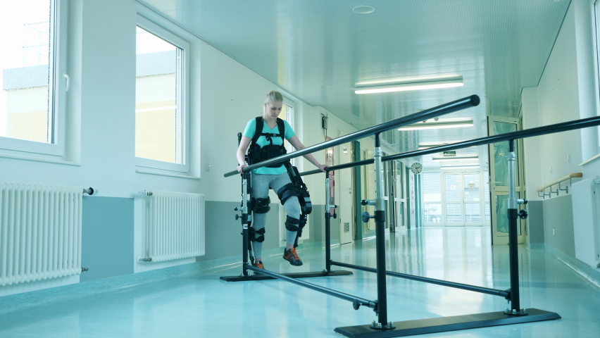 Young woman is training walking while wearing exoskeleton Royalty-Free Stock Footage #1073462090