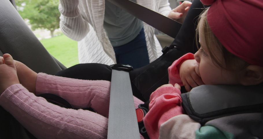 Caucasian mother closing the door after keeping her baby in safety seat in the car. motherhood, love and childcare concept
