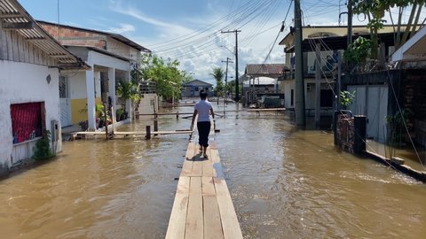 Woman walk through a wooden footbridge set up above a flooded street in Careiro da Varzea, near Manaus (AM), during the rise of Negro River due to heavy rains in Brazil.