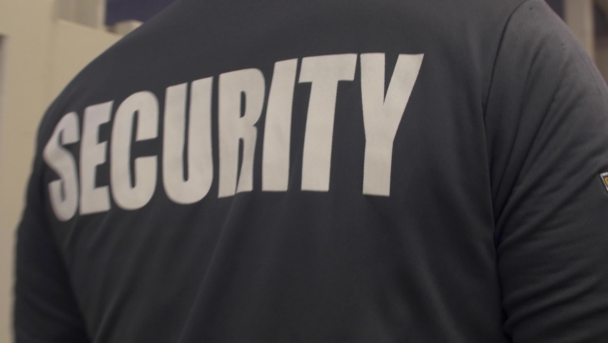 A shallow focus of security personnel walking and observing along a building's premises in 4K