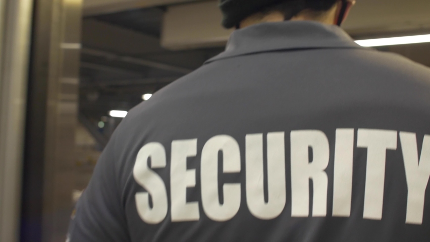 A shallow focus of security personnel walking and observing along a building's premises in 4K
