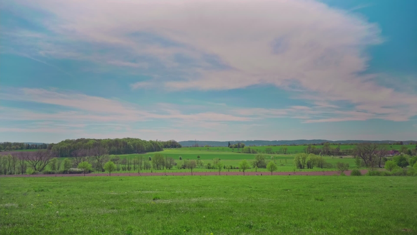 A wide grassy landscape with trees under a cloudy sky shot in HD