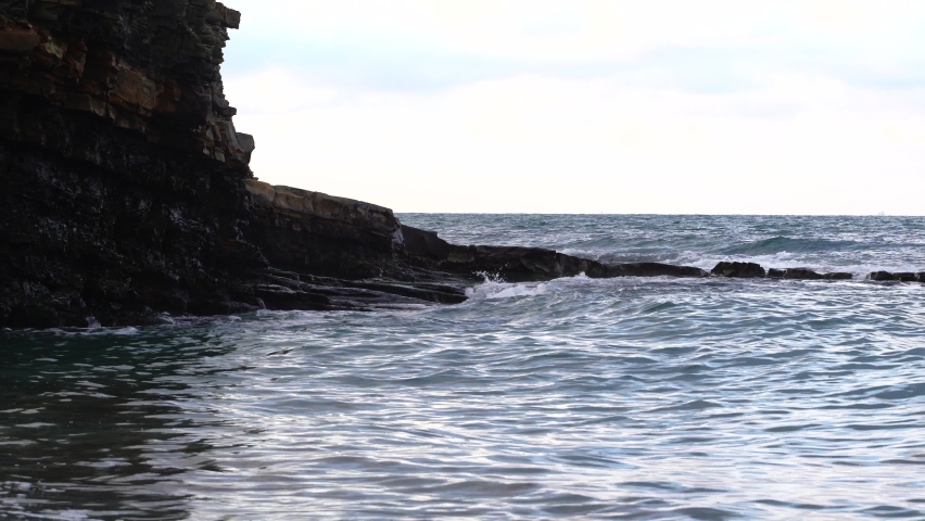 The sunrise over the calm sea casts rays of orange light into the air as the setting sun penetrates through the clouds into the picturesque calm seascape-the sea. Big waves on the sea.