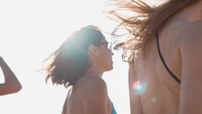 Group of pretty female friends having fun walking down sandy tropical beach in swimsuits. Interracial women chatting and laughing on summer day outdoors. Girls wearing bikini and swimwear by the sea. - Powered by Shutterstock - Get 15% off with code: PIKWIZARD15