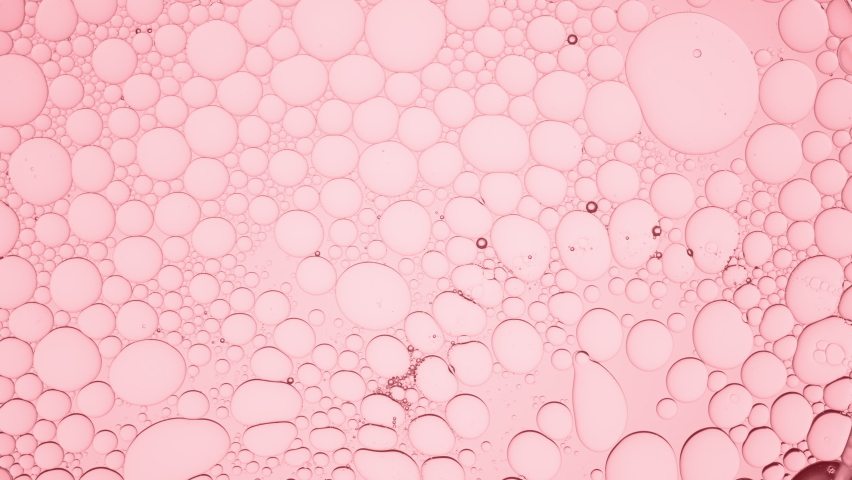Big clear bubble slides along pale pink smaller ones moving them against pink background  Macro shot of emollient ingredients for its commercial Royalty-Free Stock Footage #1073480549