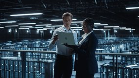Data Center Female e-Business Enrepreneur and Male IT Specialist talk, Use Laptop. Information Technology Engineer and System Administrator work in Big Cloud Computing Server Farm. Medium Wide Shot - Powered by Shutterstock - Get 15% off with code: PIKWIZARD15