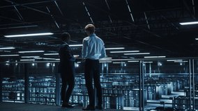 Data Center Male IT Specialist and Female e-Business Enrepreneur Talk, Use Laptop. Two Information Technology Professionals on Bridge Overlooking Cloud Computing Server Farm. Medium Wide Shot - Powered by Shutterstock - Get 15% off with code: PIKWIZARD15