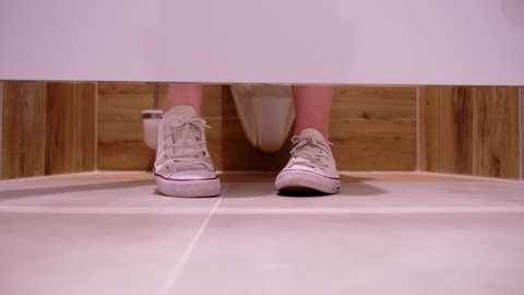 Impatient Stressed Caucasian Female Moving Her Feet While Sitting Toilet Cabin