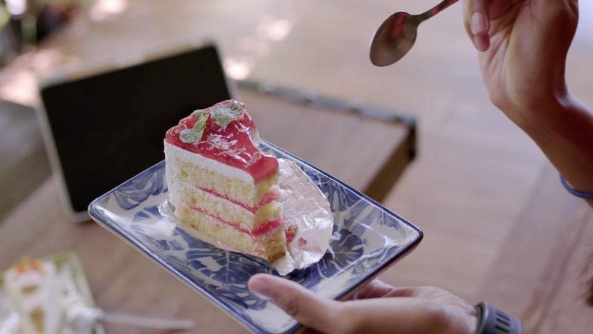 Asian womam eat cake and using labtop in Coffee Shop