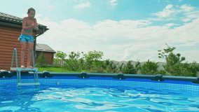 Slow motion clip: Happy boy having fun in the private pool.  White boy jumps into the pool creating a big splash. Child dives into the water in  summer. Activity of the child in the water. Happiness