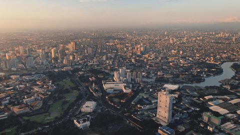 Aerial Manila city panorama business center with skyscrapers, modern buildings in Makati district. Metropolis town in sunset orange light. Philippines capital modern cityscape. Cinematic drone shot