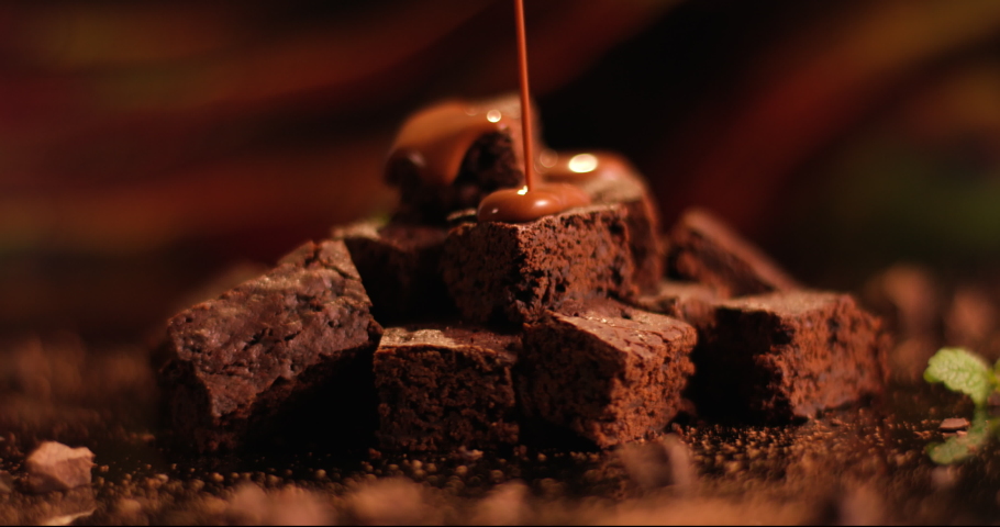 Pouring chocolate sauce on a chocolate brownie dessert. Close up of biscuit cake. Shot in slow motion with RED camera.. | Shutterstock HD Video #1073515958