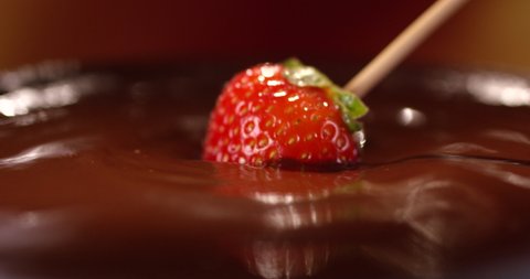 Fresh red strawberry put into a hot milk chocolate. Chocolate fondue.