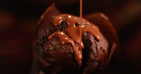 Milk chocolate sauce pouring on a muffin cake close up. Filmed in slow motion with RED camera.