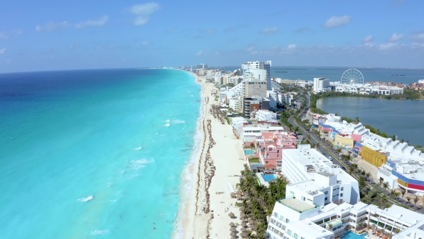 Aerial view of Cancun, Mexico showing luxury resorts and blue turquoise beach. People parasailing, swimming and tanning on the beach. Background of wonderful Caribbean beach in Cancun Royalty-Free Stock Footage #1073517101