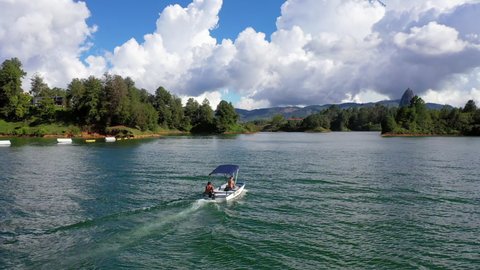 Aerial: Tourist Riding In Speed Boat During Vacation, Drone Flying Over Scenic Sea Against Cloudy Sky - Guatape, Colombia