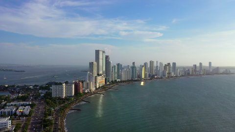 Aerial Panning Shot Of Tall Buildings Located Amidst Scenic Sea, Done Flying Over City Against Sky On Sunny Day - Cartagena, Colombia