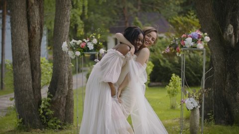 Wedding portrait of a lesbian sex couple. Two young women in wedding dresses are smiling and hugging at the wedding