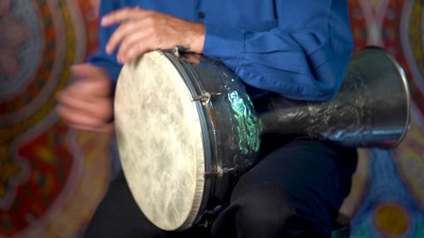 Drumming rhythm on metal Turkish daholla with arabic background.