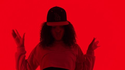 BELARUS, MINSK - MAY 11, 2021:Fashion woman dancing in rnb style.Black young model moves rhythmically. Female dancer posing on red neon background in studio.  Hip hop and break dance technique
