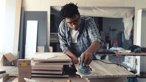 Young black man carpenter working in his workshop. Slow-motion.