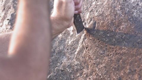 Ancient man cave painting and writing historic inscription graffiti on rock surface with iron chisel.Year old engrave on stone carve carving mason chiseling drawing work shaping prehistoric primitive.