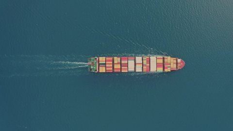 Aerial top view drone flies over to large cargo ship. Freight vessel full of containers. Huge marine craft shipping import export. Concept of sea transport logistics carriage. High quality 4k footage