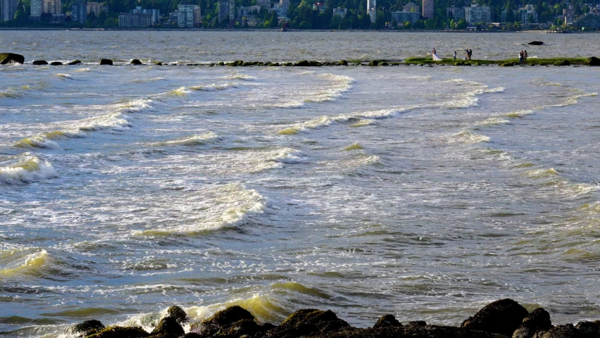 Waves crash over sandstone rock in urban area
