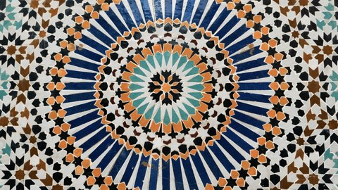 Colorful star-shaped pattern in traditional Islamic geometric design from a public fountain in Marrakech, Morocco. Made with natural colors from indigo, saffron, mint, kohl. Camera movement: rotating.