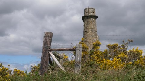 Wire Fence On The Flue Chimney Ruin Along With The Gorse Wildflowers In Carrickgollogan Hill. static shot 