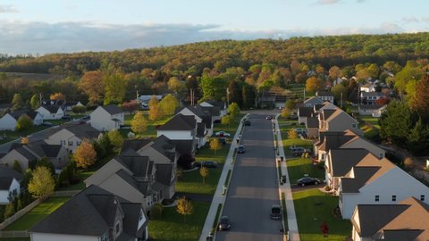 Aerial of modern American homes lining tree in traditional USA suburb. Beautiful golden hour light.
