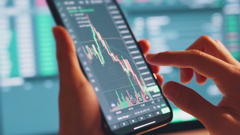 Closeup - Woman is checking Bitcoin price chart on digital exchange on smartphone, cryptocurrency future price action prediction.