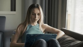 Woman on sofa at home making video call using laptop on self isolation