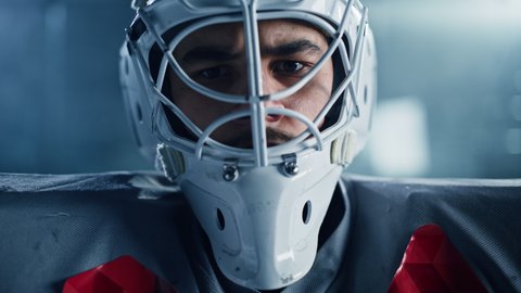Ice Hockey Rink Arena: Portrait of Brutal Professional Goalkeeper, Wearing Goaltender Mask, Looking at Camera Seriously. Focused Goalie, Determined to Win. Confident Champion Athlete. Close-up Shot
