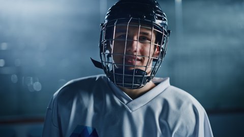 Ice Hockey Arena: Portrait of Confident Professional Player, Wearing Helmet, Looking at Camera and Smiling. Close-up Shot